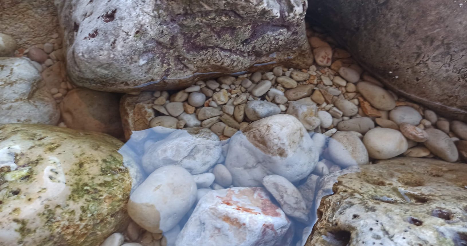 Transparent water between stones. Utjeha nude beach