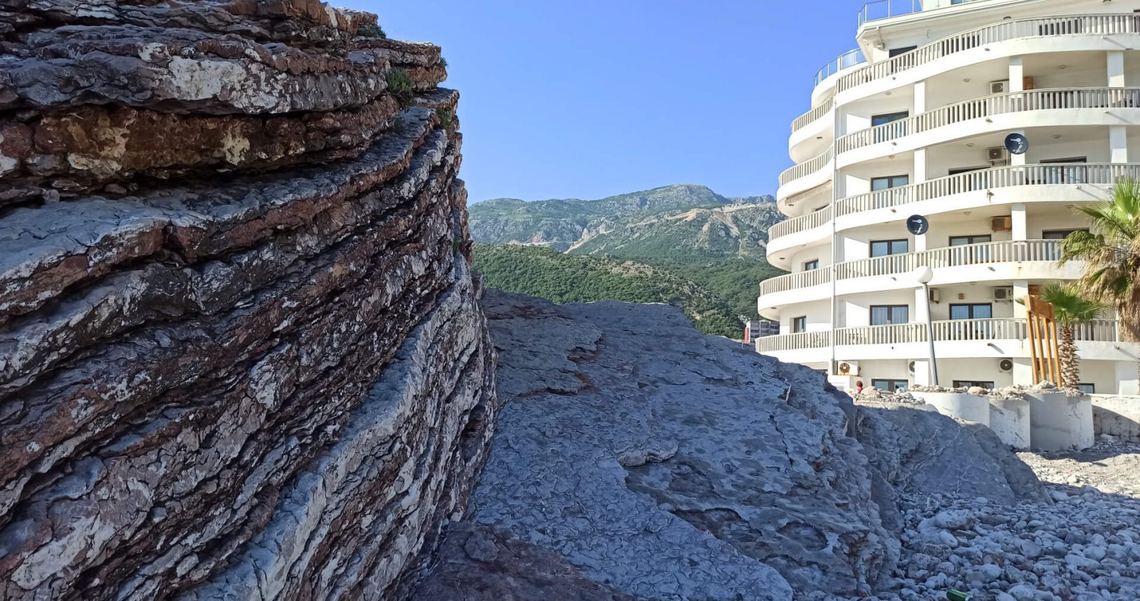 Building and background mountains at Rafailovici rocky beach